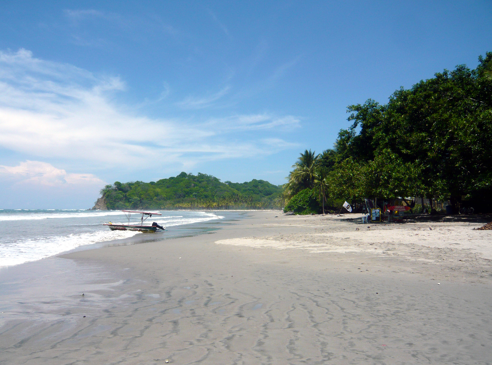 The beach at Sámara with a small boat pulled up on the sand
